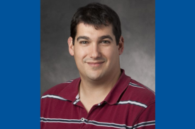 Pictured is Dr. Ben Goldstein, a man with light skin short black hair, smiling and wearing a maroon and white striped polo shirt